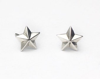 May include: A pair of silver star-shaped earrings. The stars have a 3D design and are slightly raised.