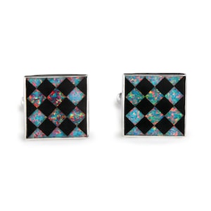 May include: A pair of silver cufflinks with a black and iridescent opal checkered pattern.