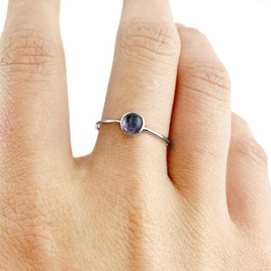 May include: A silver ring with a small, round, purple gemstone.