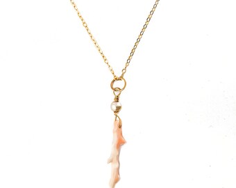 May include: A delicate gold chain necklace featuring a pink coral branch pendant and a single pearl bead.