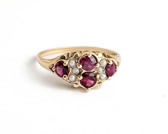 May include: A gold ring with a cluster of red gemstones and white pearls. The ring is set in a delicate, floral design.
