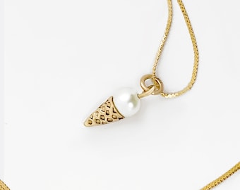 May include: A gold chain necklace with a small pearl and gold ice cream cone pendant.
