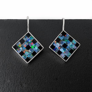 May include: A pair of silver earrings with black and iridescent opal mosaic square-shaped pendants.