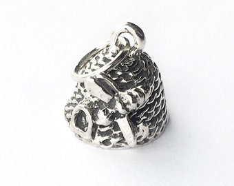 May include: A silver charm in the shape of a ball of yarn with knitting needles. The charm has a loop at the top for attaching to a bracelet or necklace.