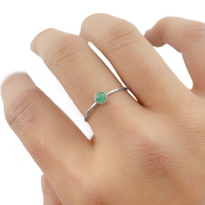 May include: A silver ring with a small, round, green gemstone.