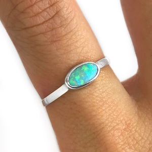 May include: A silver ring with a light blue oval opal gemstone.
