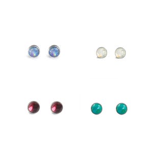 Peut inclure: Un ensemble de six boucles d'oreilles à clous avec des pierres de différentes couleurs. Les boucles d'oreilles sont en argent et ont une forme ronde. Les pierres sont bleues, blanches, rouges et vertes.