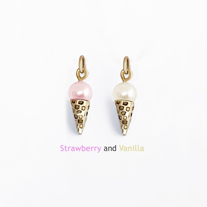 May include: Two gold ice cream cone charms, one with a pink pearl and the other with a white pearl. "Strawberry and Vanilla" is written below the charms.