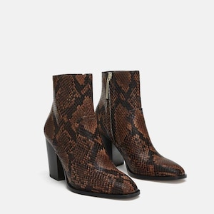 May include: A pair of brown and black snake-print ankle boots. The boots have a pointed toe, a block heel, and a zipper closure. The heel height appears to be approximately 3 inches.