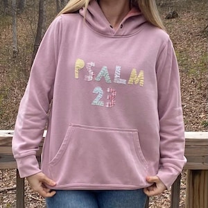 May include: A pink hoodie with a large patchwork design that says "PSALM 23" on the front.