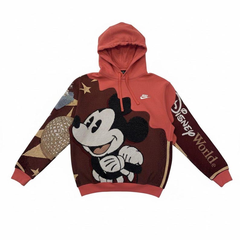 May include: Red and brown hooded sweatshirt featuring a large Mickey Mouse design. The left sleeve has a graphic of a globe and stars, while the right sleeve displays "Disney World". The Nike logo is visible on the chest.