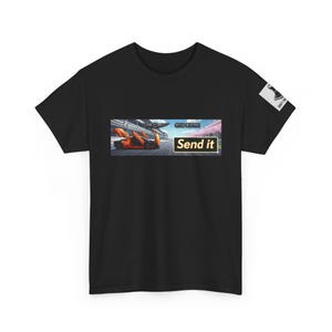 Puede incluir: Camiseta negra con un gráfico de un coche de carreras naranja en una pista y las palabras "Send it". Un pequeño cuadrado blanco con un gráfico negro está en la manga derecha.