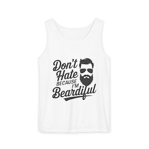 May include: White vest top featuring the text "Don't Hate Because I'm Beardiful" in black script. A graphic of a bearded man wearing sunglasses is next to the text. The vest top is a casual garment.