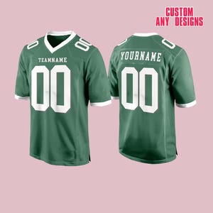 May include: Two green football jerseys with white accents. The front jersey has "TEAMNAME" above the number "00". The back jersey has "YOURNAME" above the number "00". The text "CUSTOM ANY DESIGNS" is in the top right corner.
