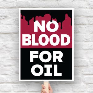 Op de afbeelding: Een protestbord met de woorden "NO BLOOD FOR OIL" in dikke witte letters. De bovenste helft is bordeauxrood met zwarte druppels en de onderste helft is zwart. Het bord wordt vastgehouden door een houten stok.