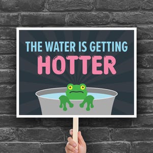 May include: A sign with the text "THE WATER IS GETTING HOTTER" in blue and pink. A cartoon frog is in a bucket of water. The sign is held by a wooden stick.