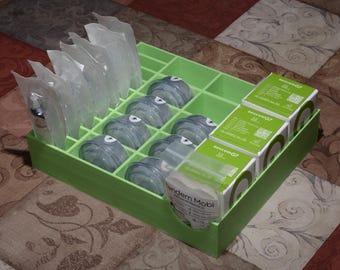Puede incluir: Una caja de almacenamiento de plástico verde con múltiples compartimentos. La caja contiene recipientes de plástico transparente, algunos con tapa verde, y varias cajas pequeñas con etiquetas blancas. Las etiquetas tienen el texto "Medtronic MiniMed 640G".