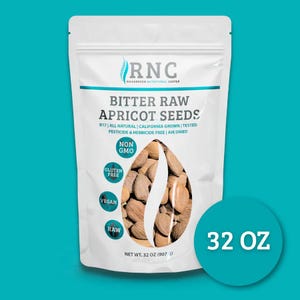 Op de afbeelding: Een witte zak met bittere rauwe abrikozenpitten van Richardson Nutritional Center. De zak toont de tekst "BITTER RAW APRICOT SEEDS", "NON GMO", "GLUTEN FREE", "VEGAN" en "RAW". De zak bevat 907 g zaden.