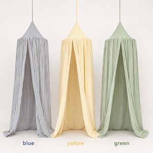 May include: Three hanging fabric canopies featuring vertical stripes in blue, yellow, and green. Each canopy has a conical top and drapes down to the floor. The text blue, yellow, and green is printed below each corresponding canopy.