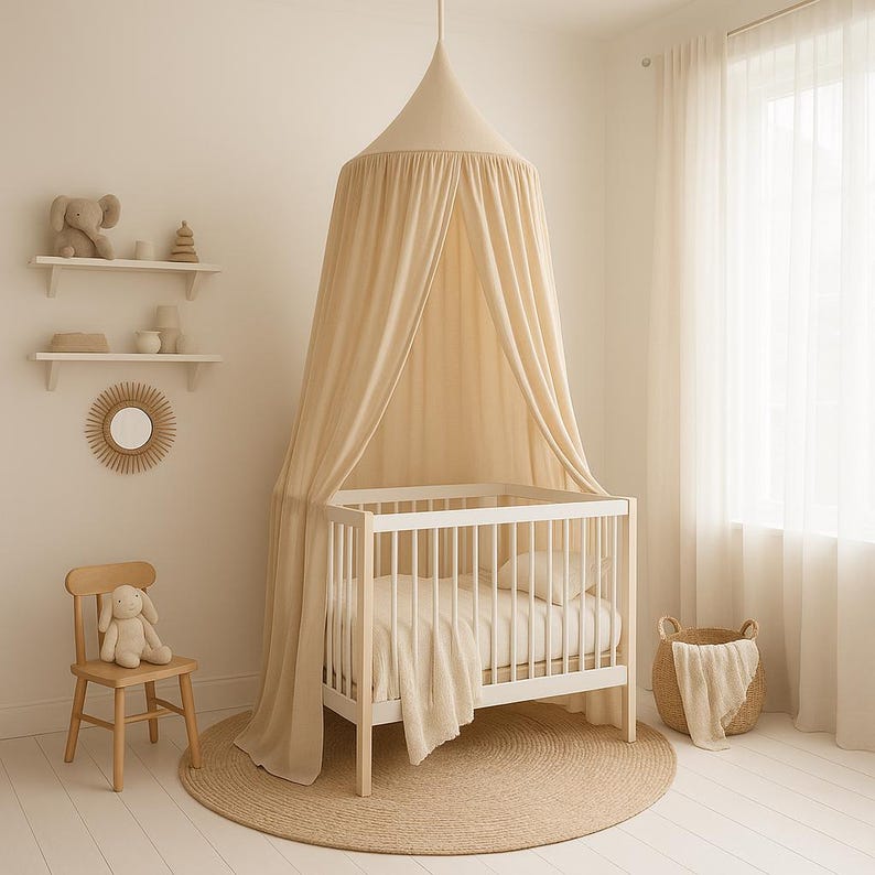 May include: A nursery scene with a white crib, a beige canopy, and a round jute rug. A wooden chair with a stuffed bunny sits nearby. Shelves with decorative items and a woven basket complete the soft, neutral-toned space.
