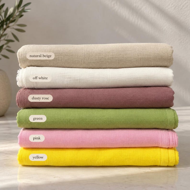 May include: A stack of six folded fabric pieces in natural beige, off white, dusty rose, green, pink, and yellow. Each piece features a visible woven texture and a small white label identifying the color as natural beige, off white, dusty rose, green, pink, or yellow.