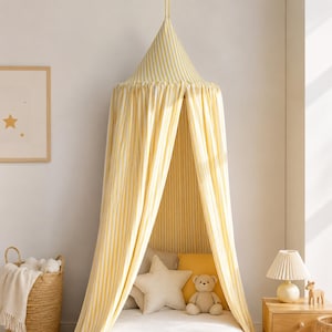 May include: A conical bed canopy featuring vertical yellow and white stripes, suspended from a single point. The fabric drapes downward to create a semi-enclosed space, with a pointed top section and long, flowing panels that reach toward the floor.