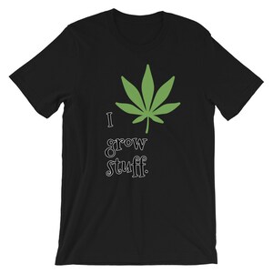 May include: Black t-shirt with a green cannabis leaf graphic and the text "I grow stuff." The design features a stylized leaf and playful lettering. A casual, short-sleeved tee.