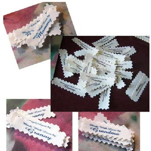 Puede incluir: Un mont&oacute;n de etiquetas de tela blanca con bordes festoneados. Las etiquetas est&aacute;n impresas con el texto "Made With Love by Mommy", "Made With Love by Granny" y "Made With Love by Grandma".
