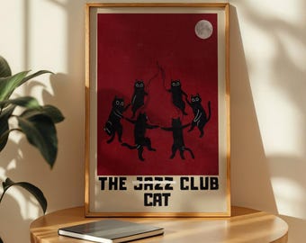 Może przedstawiać: Oprawiony wydruk artystyczny przedstawiający stylizowaną ilustrację sześciu czarnych kotów tańczących w kręgu pod pełnią księżyca na ciemnoczerwonym tle. Tekst "THE JAZZ CLUB CAT" znajduje się na dole. Wydruk jest w drewnianej ramie.