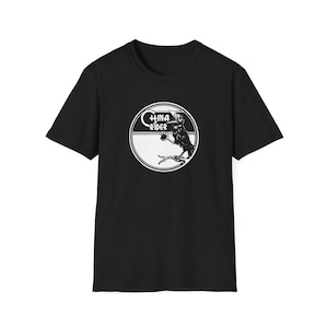 May include: Black t-shirt featuring a white circular graphic with the text "CHINA RIDER" and an illustration of a bird-like figure. The graphic is centered on the front of the short-sleeved shirt.