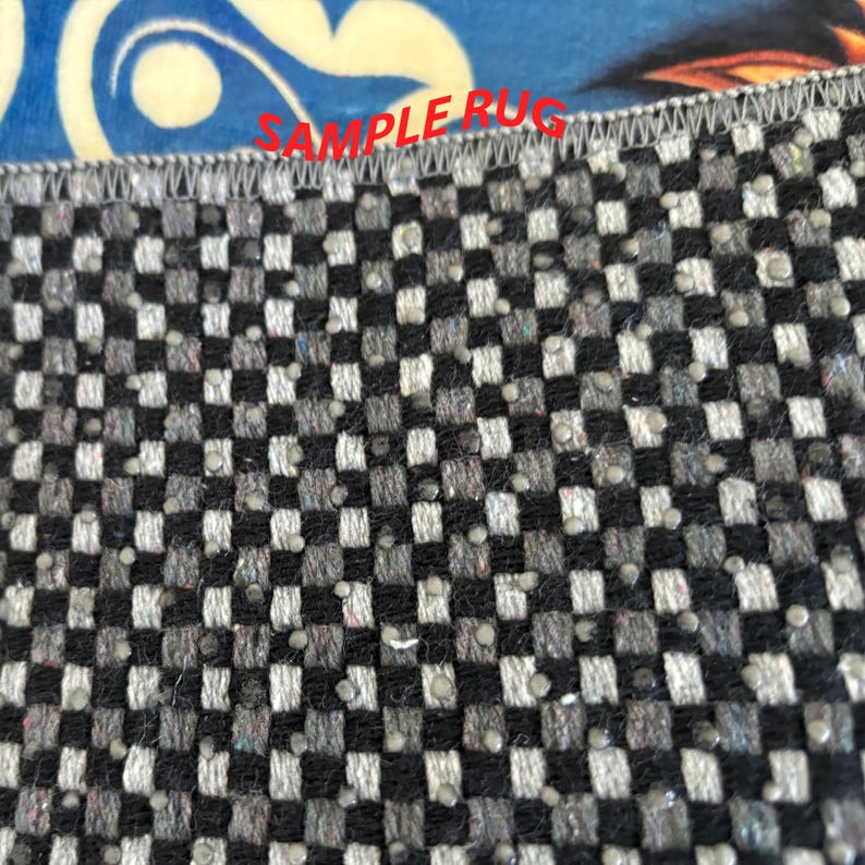 May include: Close-up of a rug with a checkered pattern in black, gray, and white. The rug has a textured surface with small, raised dots. The text "SAMPLE RUG" is visible in red across the top edge.