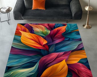 May include: A rectangular area rug featuring a vibrant, abstract design of large, overlapping leaves. The leaves display a gradient of colors, including orange, red, purple, teal, and green. The rug is placed on a gray floor, with a black sofa and orange pillow in the background.