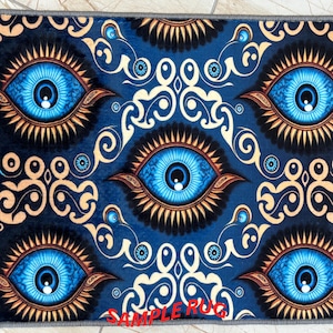 May include: A blue rug with a repeating pattern of large, stylized blue eyes with gold and black accents. The rug has a dark blue background with cream-colored scrollwork. The text "SAMPLE RUG" is printed in red at the bottom.