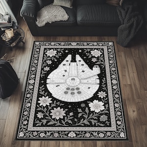 May include: A black and white area rug with a Millennium Falcon spaceship design. The rug has a floral border with white flowers and vines. The spaceship is centered on a black background.