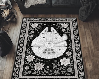 Może przedstawiać: Czarno-biały dywan z motywem statku kosmicznego Millennium Falcon. Dywan ma kwiatową bordiurę z białymi kwiatami i winoroślami. Statek kosmiczny jest wyśrodkowany na czarnym tle.