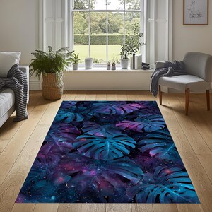 May include: A rectangular area rug featuring a vibrant design of large, stylized monstera leaves in shades of blue and purple, set against a dark, starry background. The rug is placed on a hardwood floor, adding a touch of nature-inspired decor to the room.