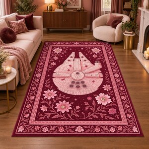 Può includere: Un tappeto rettangolare con uno sfondo bordeaux intenso che presenta un'illustrazione centrale dell'astronave Millennium Falcon circondata da intricati viticci floreali rosa chiaro, fiori e un bordo decorativo di piccoli fiori.