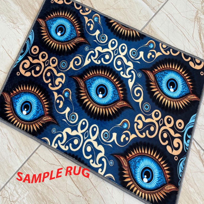 May include: A rectangular rug featuring a repeating pattern of large blue eyes with gold and brown accents against a dark blue background. The rug has a gray border and the text "SAMPLE RUG" in red.