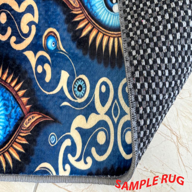 May include: A section of a blue rug with an eye design and gold swirls. The rug's edge is visible, showing a gray border and a checkered backing. The text "SAMPLE RUG" is in the bottom right corner.