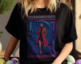 Może przedstawiać: Czarny T-shirt z nadrukiem graficznym przedstawiającym kobietę w czerwonym płaszczu i czarnej sukience idącą ulicą miasta z neonowym szyldem, na którym widnieje napis "Vista" i "2080 Hotel". Tekst na koszulce brzmi "Overdressed for the breakdown...and still showed up".