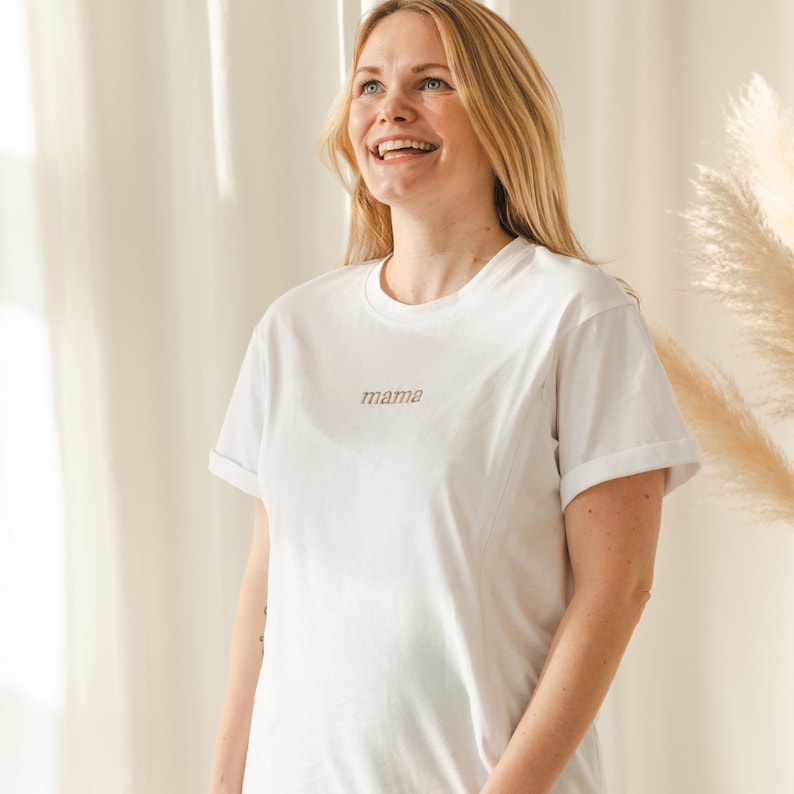 May include: White t-shirt with the word "mama" embroidered in brown on the front.