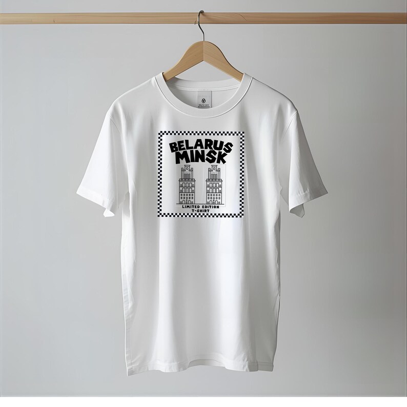 May include: White t-shirt with a black and white graphic featuring the text "Belarus Minsk" and illustrations of two buildings. The graphic is framed by a checkered border, with "Limited Edition T-Shirt" text below.