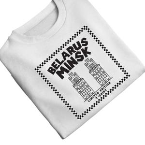 May include: White sweatshirt featuring a black and white graphic. The graphic includes the words "BELARUS MINSK" and two stylized building illustrations within a checkered border. The text "LIMITED EDITION T-SHIRT" is also present.