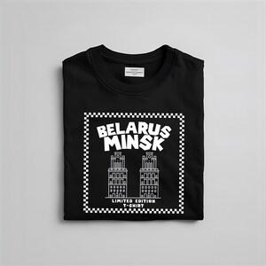 May include: Black crew neck t-shirt with a white graphic that reads "BELARUS MINSK" above a line drawing of two buildings. The graphic is framed with a checkered border and the text "LIMITED EDITION T-SHIRT" is below the buildings.
