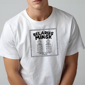 May include: White t-shirt featuring a black and white graphic of two buildings with the text "BELARUS MINSK" above and "LIMITED EDITION T-SHIRT" below. The design is framed by a checkered border.