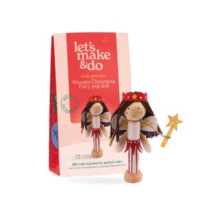 Puede incluir: Un kit de manualidades para una muñeca de hada de Navidad de madera con una caja roja y blanca con el texto let's make & do, create your own, Wooden Christmas Fairy peg doll y QR code included for guided video. Una muñeca terminada con pelo de lana marrón, una corona roja, alas blancas y una varita de estrella amarilla se encuentra delante.