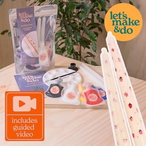 Peut inclure: Un kit créatif pour réaliser des bougies décoratives. Le kit comprend deux bougies blanches, de la peinture, des pinceaux et une palette. Les bougies ont un motif de fraises et de fleurs. Le kit est accompagné d'un tutoriel vidéo. Let's Make & Do.
