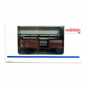 May include: A brown model train freight car, displayed in its original packaging. The car features detailed side panels and a black undercarriage. The packaging includes the brand name "märklin" in red and white.