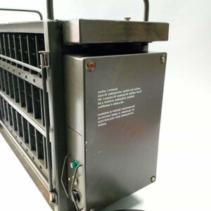 Peut inclure: Appareil industriel en m&eacute;tal vert olive avec une poign&eacute;e. Il comporte des fentes verticales, un panneau de commande avec un voyant rouge et un cordon d'alimentation. L'appareil a une poign&eacute;e sur le dessus et du texte sur le c&ocirc;t&eacute;.