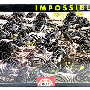 Op de afbeelding: Een puzzel van 500 stukjes met een dichte verzameling zebra's met zwart-witte strepen. Het woord "IMPOSSIBLE" staat in gele letters. De puzzel is van het merk EDUCA.